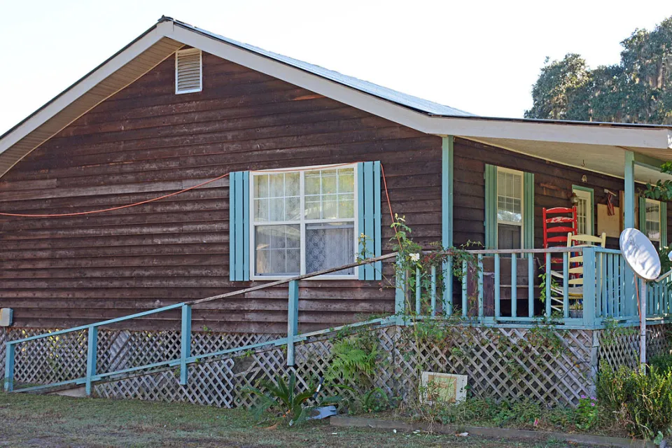 Side view of a wooden-sided house with sky-blue shutters.